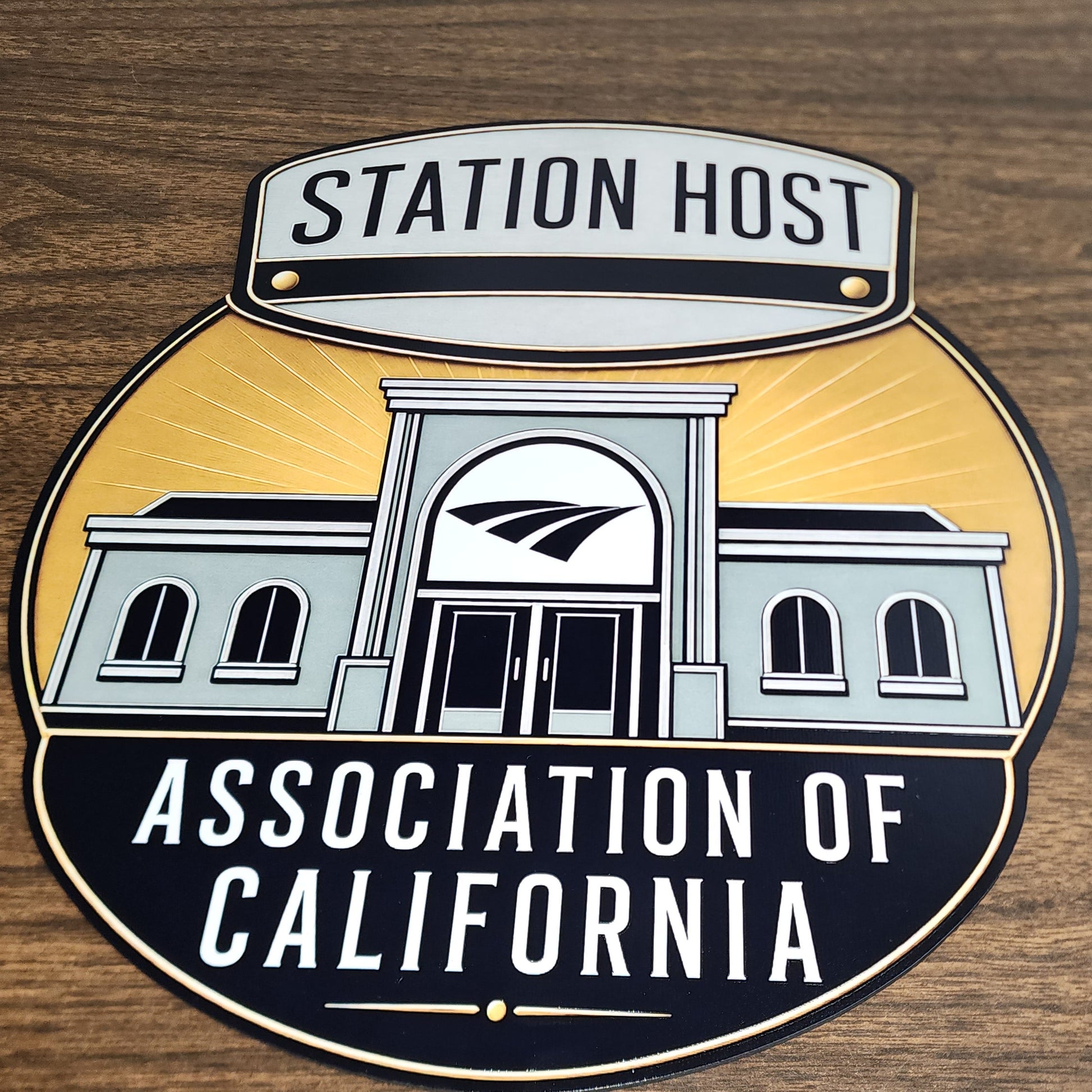 Logo of the Station Host Association of California on a wooden background