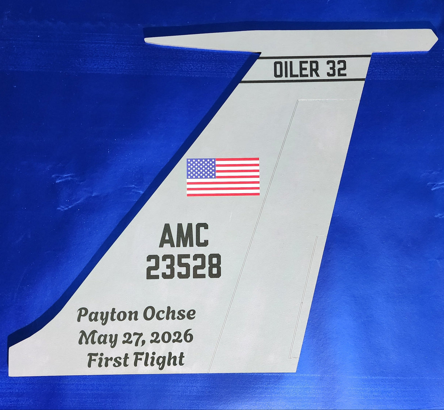A model airplane wing with text and an American flag on a blue background